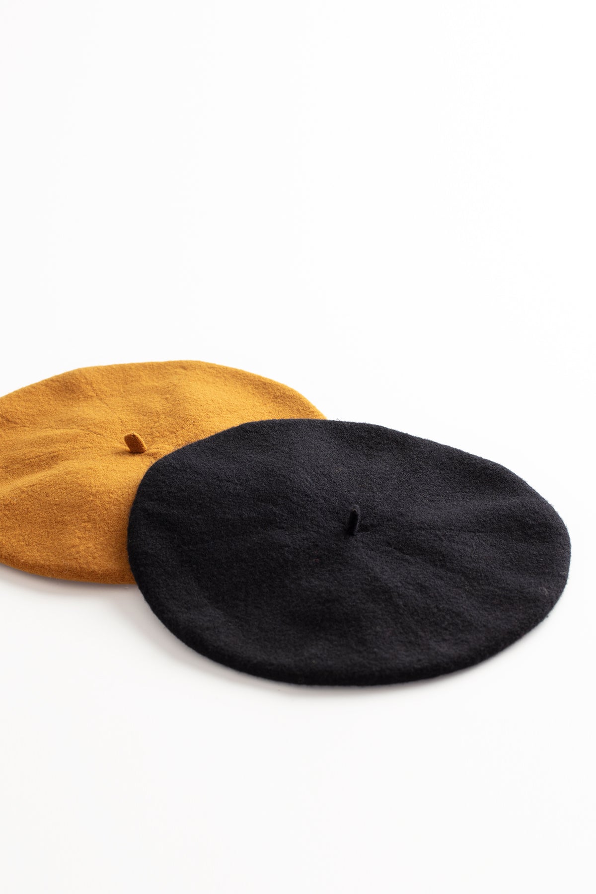 Two Gigi berets by Hansel From Basel, made of a luxurious Merino wool blend, showcased on a pristine white surface.-615365836881
