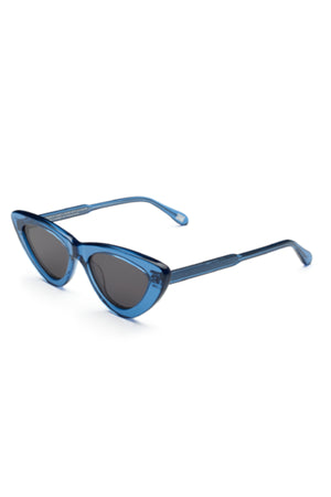 The 006 BY CHIMI EYEWEAR by Chimi features blue cat-eye frames with dark lenses, shown on a white background at an angle highlighting both front and side—a stylish unisex option from your favorite eyewear brand.