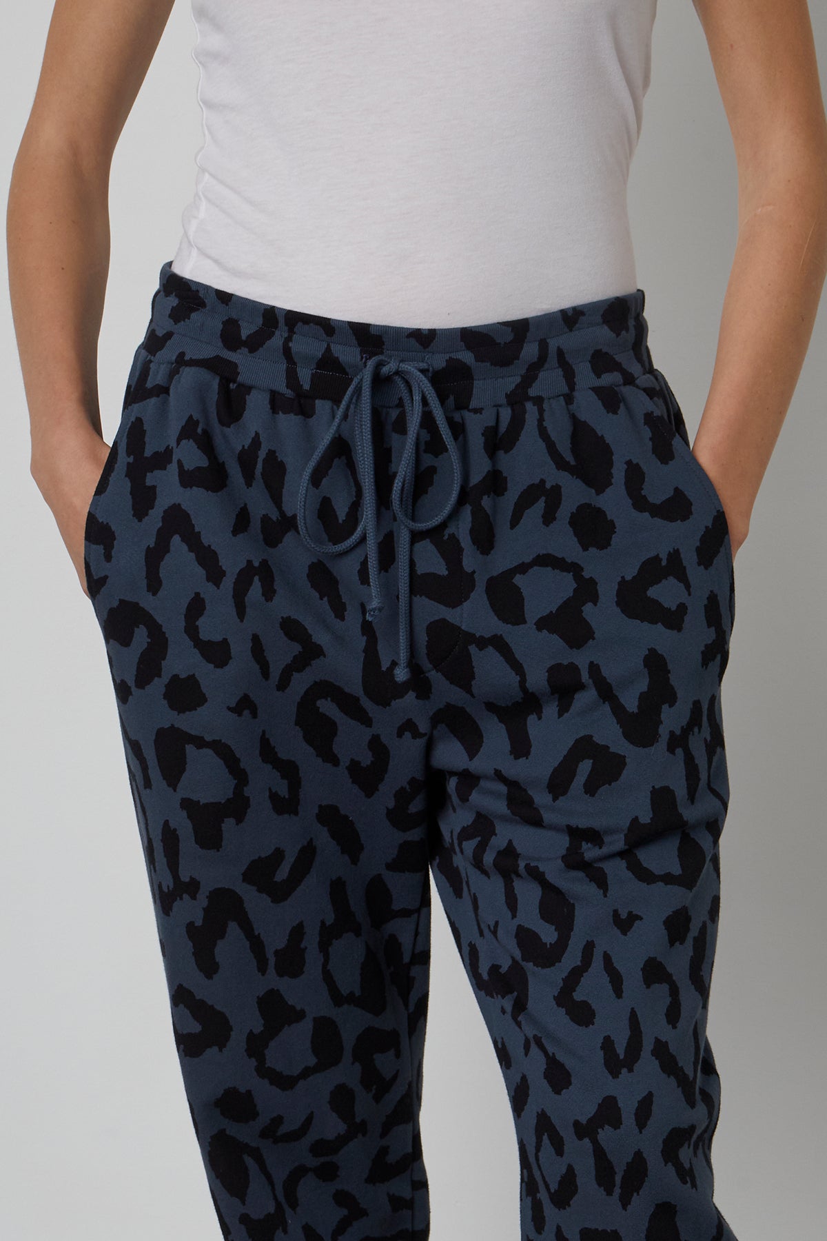 A woman donning the Velvet by Graham & Spencer GWEN PRINTED JOGGER, embodying a low-key jogger style in the form of black and blue leopard print jogging pants.-23119953592513