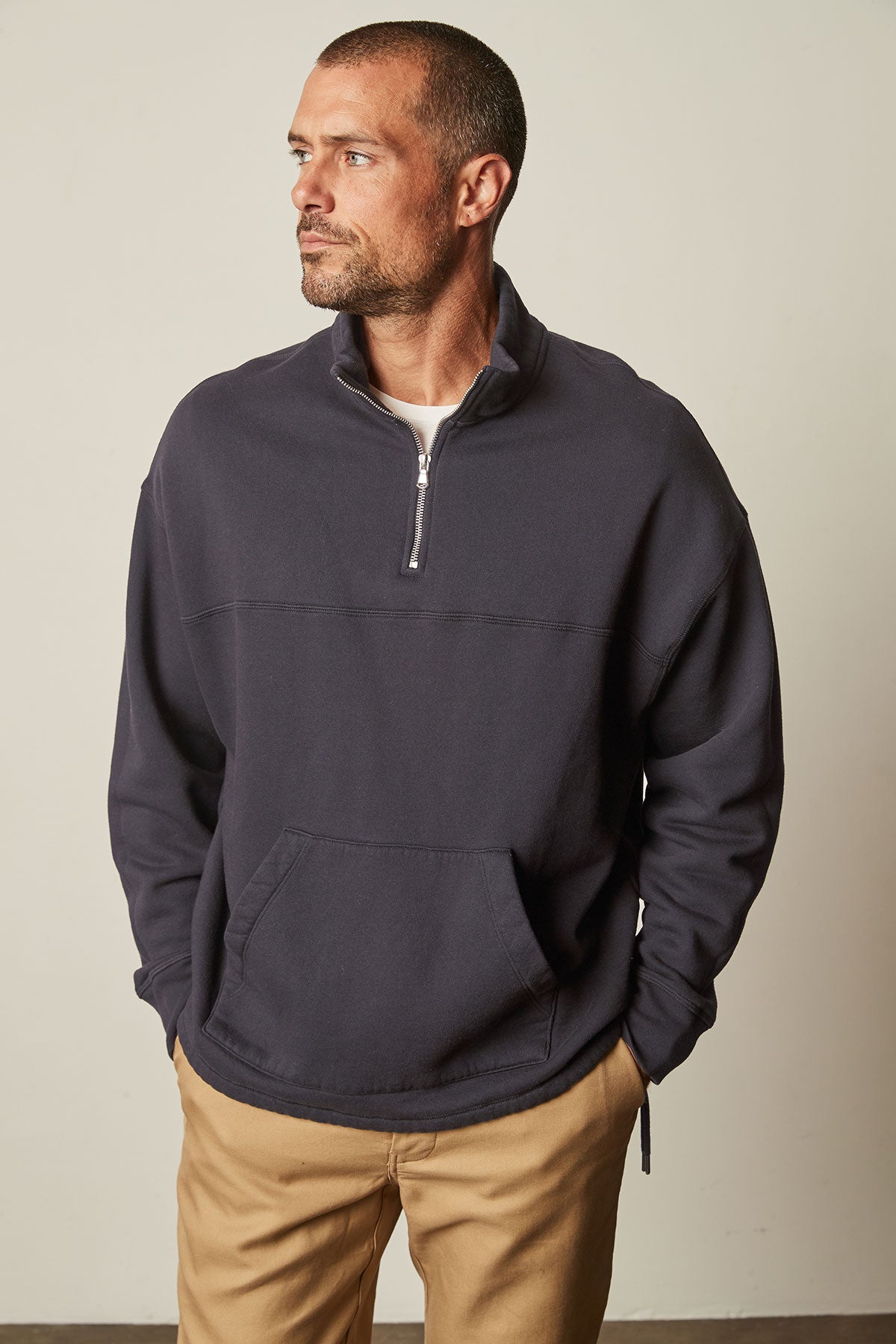 A man wearing a Velvet by Graham & Spencer BALDWIN QUARTER-ZIP SWEATSHIRT, made of a heavier knit fabric, and khaki pants.