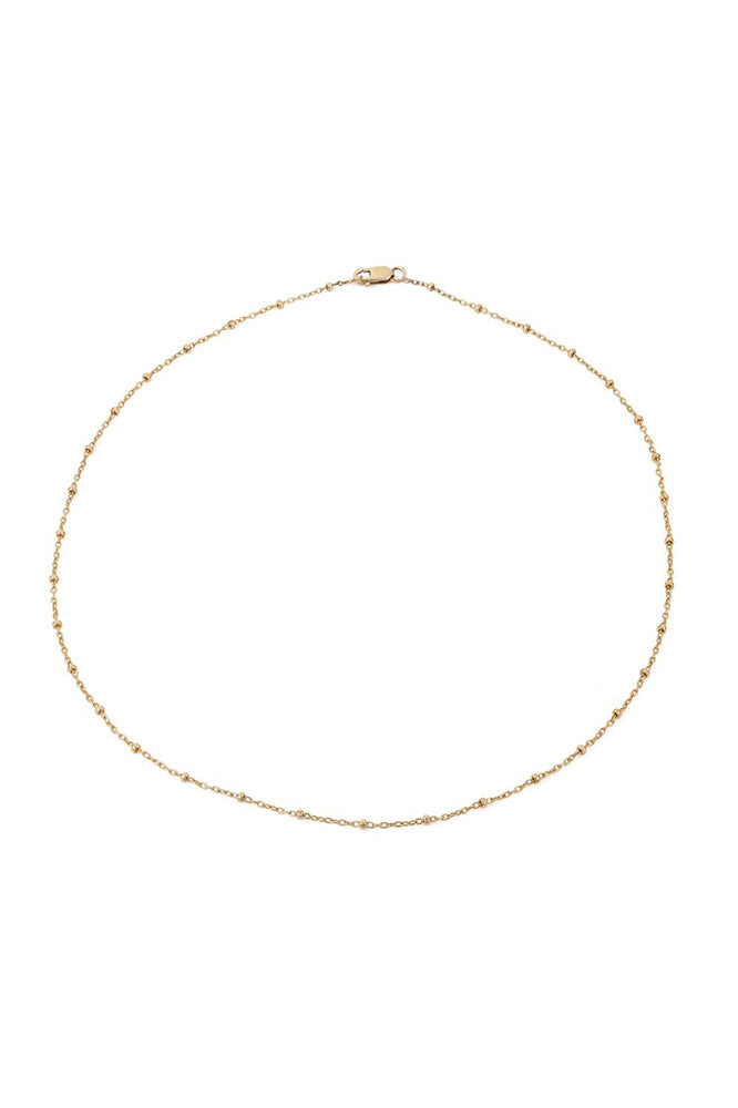 The DOT CHAIN CHOKER by Mara Carrizo Scalise is a delicate gold chain necklace with small, evenly spaced links and a lobster clasp, beautifully presented on a white background.