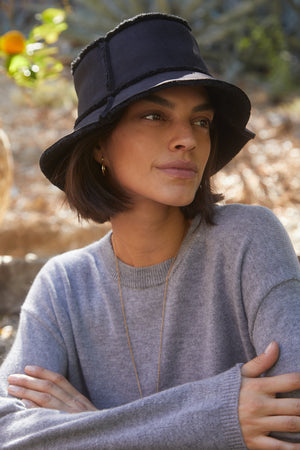 A woman wearing a REVERSIBLE FAUX SHEARLING BUCKET HAT by Velvet by Graham & Spencer.