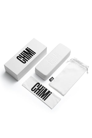 A 006 BY CHIMI EYEWEAR box, a rectangular white case, drawstring pouch, and branded cleaning cloth from Chimi are displayed on a white background—everything included for your new unisex shades.