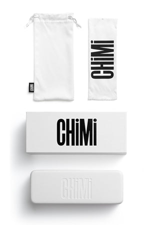 A white drawstring pouch, cleaning cloth, box, and hard case—all with bold “CHIMI” branding—highlight the European-made quality of Chimi Eyewear 003, a premium unisex accessory.