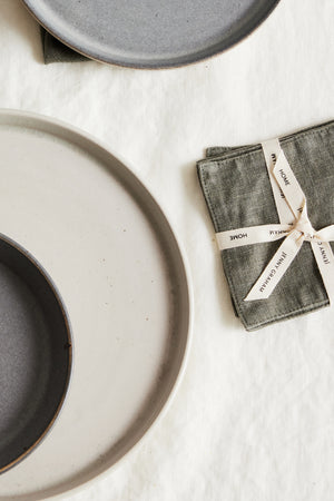 a set of LINEN COASTERS (SET OF 4) and a napkin on a white surface.