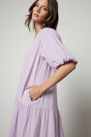The model is wearing a Velvet by Graham & Spencer PAULINE COTTON GAUZE MIDI DRESS with ruffled sleeves.
