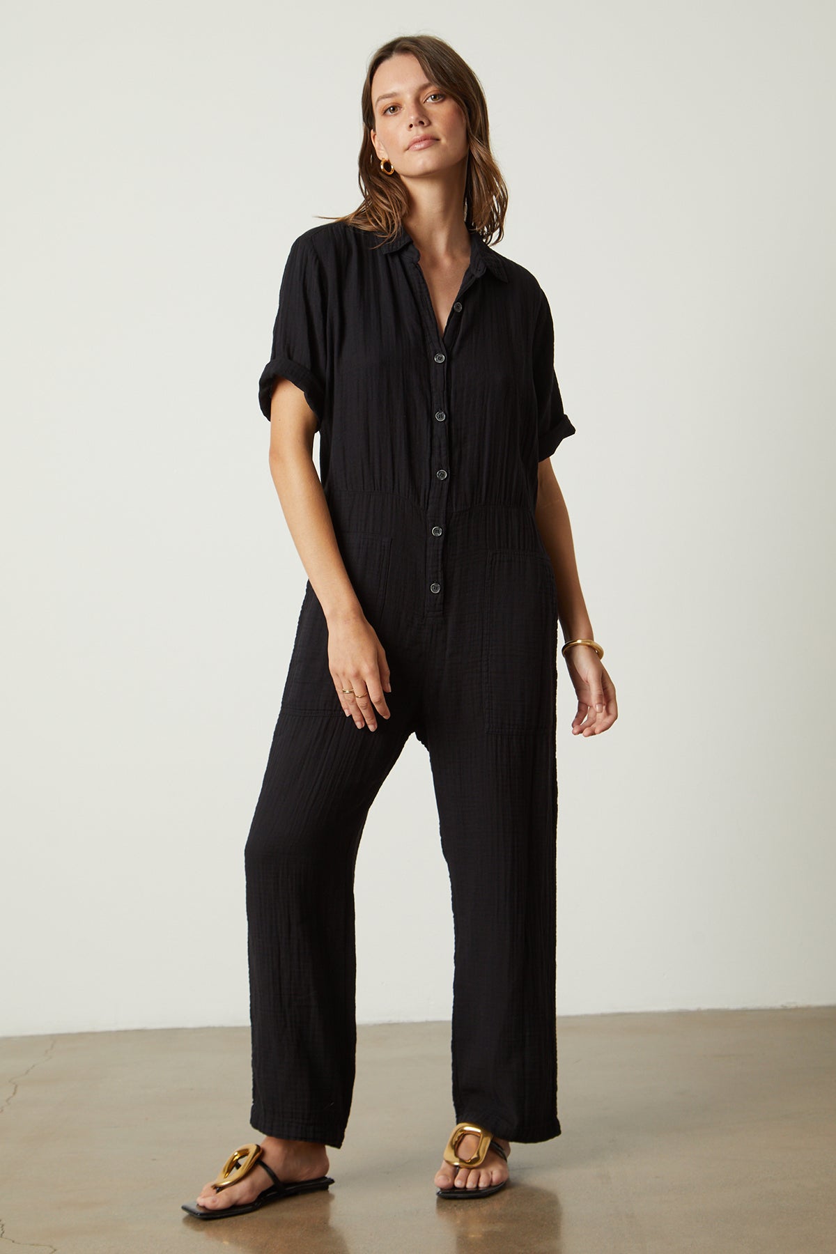 Elia jumpsuit in black with gold hoop earrings, bangle bracelet and sandals full length front-26079039652033