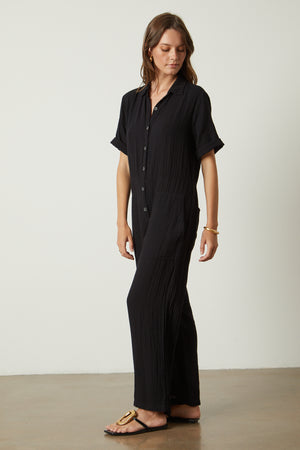 Elia jumpsuit in black with gold hoop earrings, bangle bracelet and sandals full length front & side