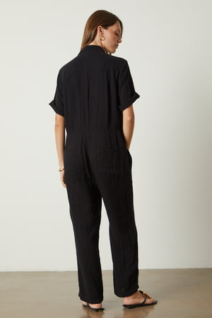 Elia jumpsuit in black with gold hoop earrings, bangle bracelet and sandals full length front back