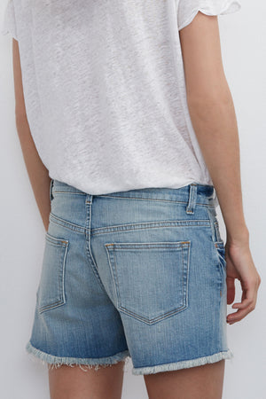 A person wearing a white t-shirt and Velvet by Graham & Spencer's Cindy Frayed Hem Boyfriend Shorts in blue, viewed from the back.