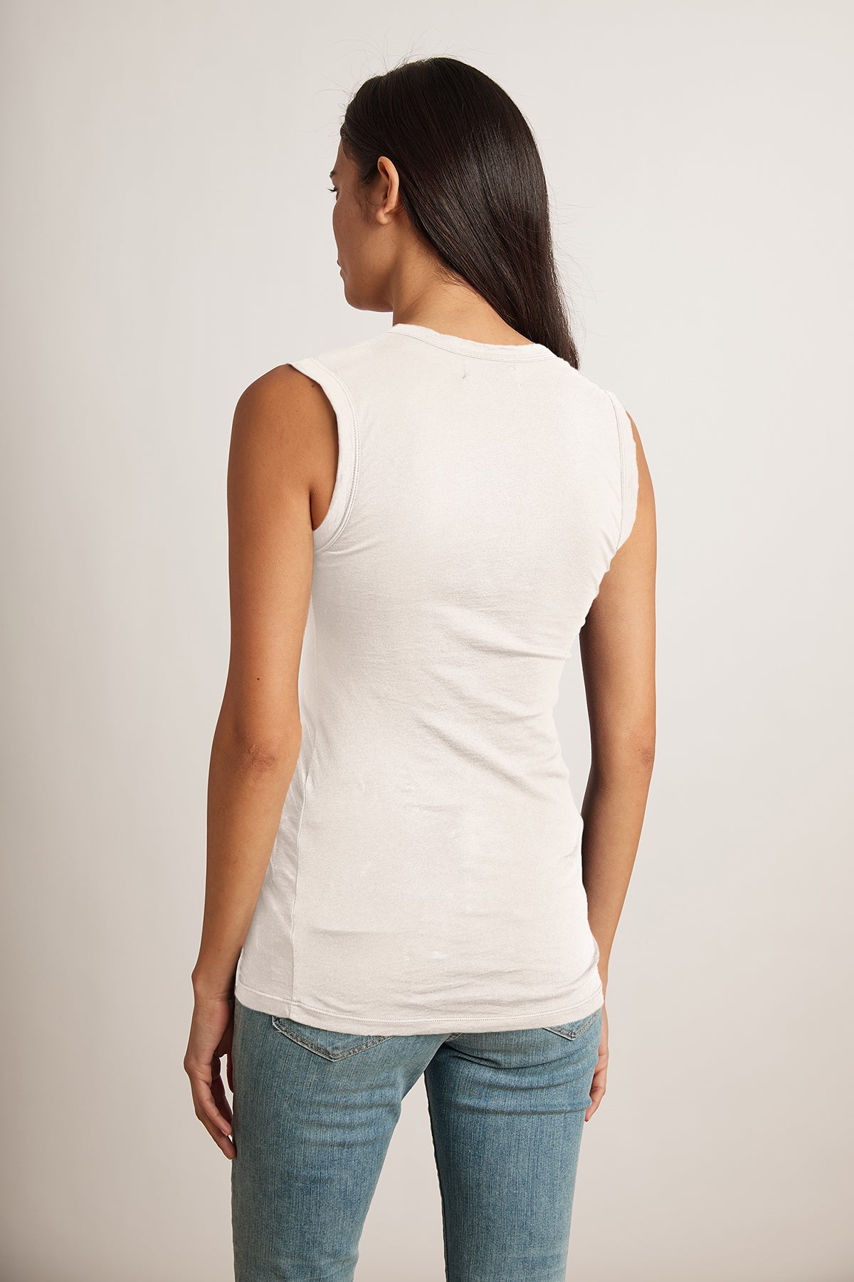 The back view of a woman wearing jeans and a Velvet by Graham & Spencer ESTINA GAUZY WHISPER FITTED TANK TOP.