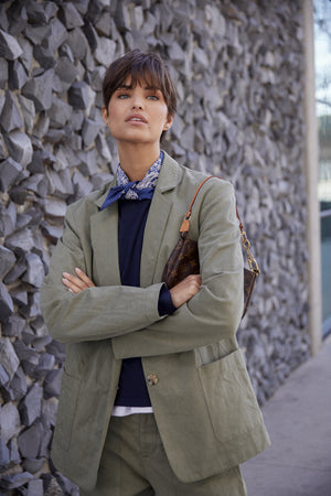 a woman in a Velvet by Jenny Graham ECHO BLAZER standing next to a wall.
