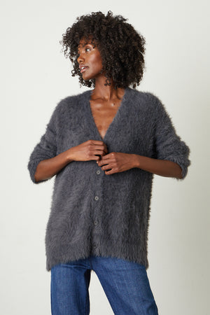 Model buttoning front of Barb Feather Yarn Button Front Cardigan in charcoal grey