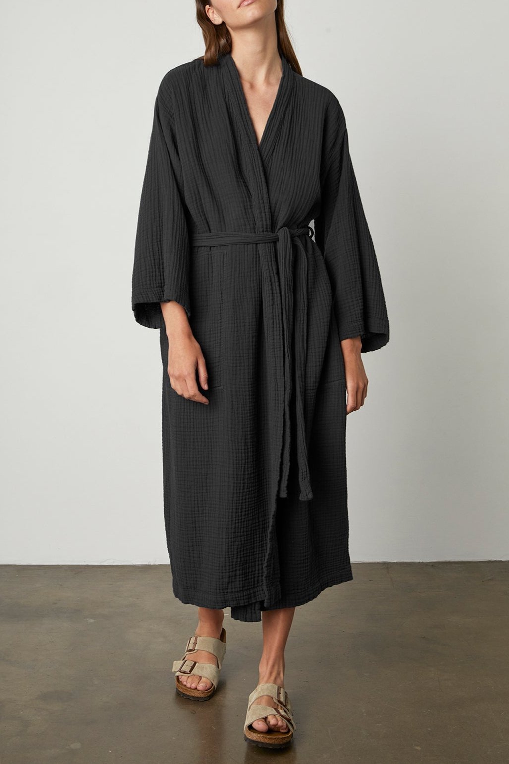 A woman wearing a black Cotton Gauze Robe by Jenny Graham Home and sandals.-23556237983937