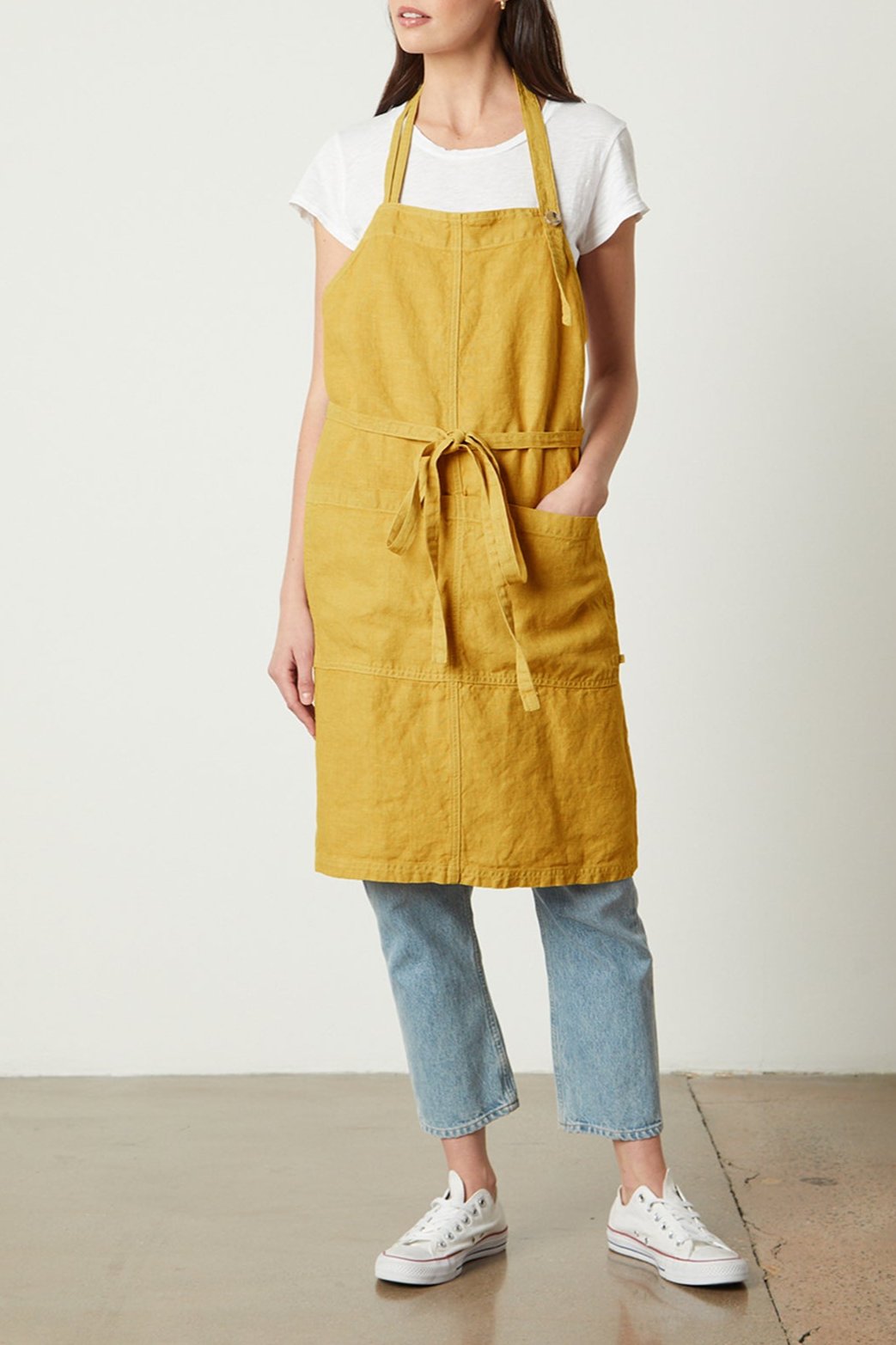 A woman wearing a yellow Jenny Graham Home linen apron made of durable linen with an adjustable neck strap.