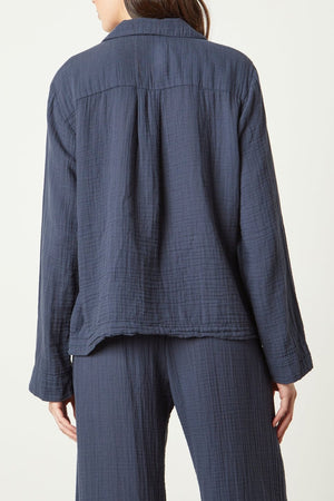 The back view of a woman wearing a blue linen PAJAMA SHIRT from Jenny Graham Home.