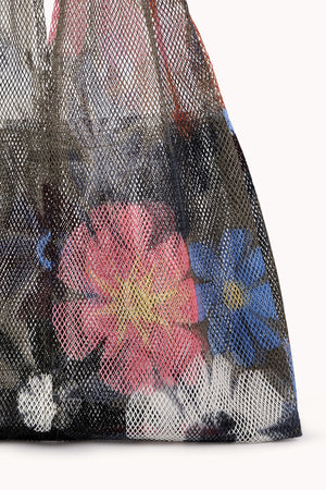 A LARGE FLORAL PRINT MESH TOTE BY EPICE from Epice, featuring bold colors and vibrant floral prints, holds assorted luxe accessories.