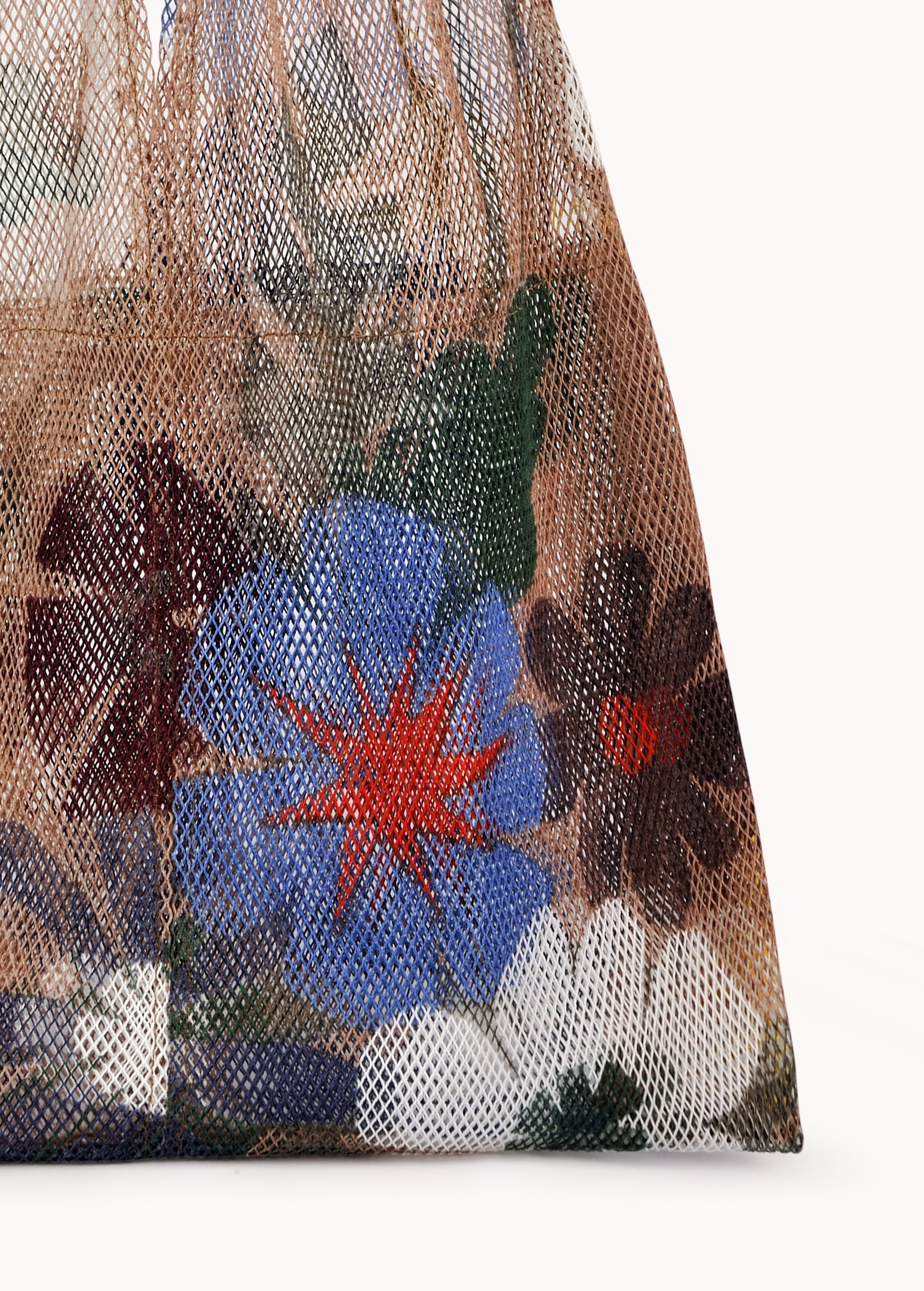 Close-up of the Large Floral Print Mesh Tote by Epice, displaying vibrant color mixes in its floral design against a simple backdrop—a truly luxurious accessory.
