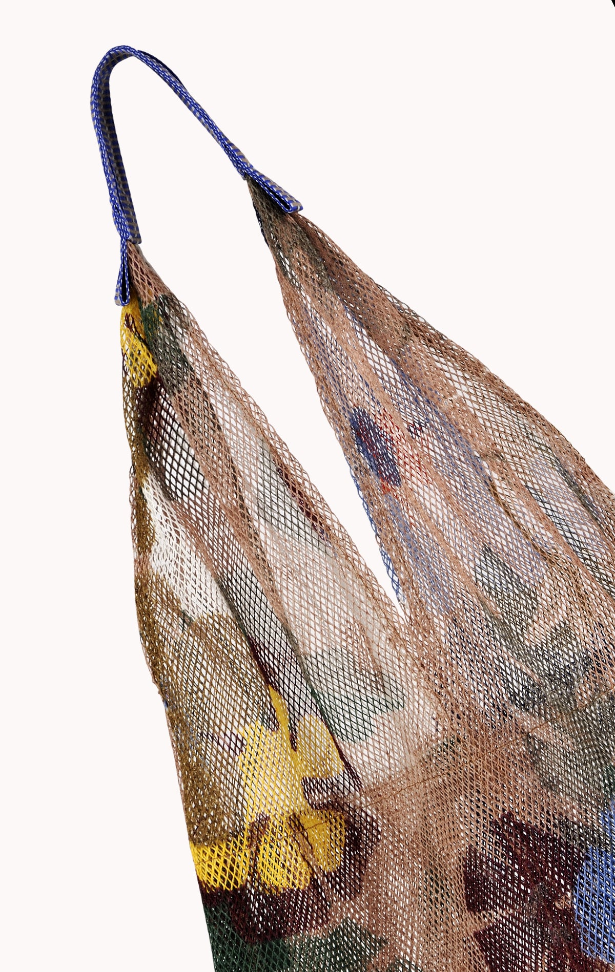 A close-up of the 'Large Floral Print Mesh Tote by Épice' with floral fabric inside and blue handles highlights Epice's bold color combinations in luxury accessories, set against a plain background.-24508344271041