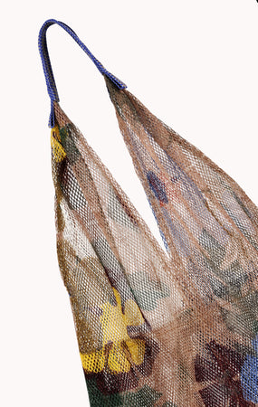 A close-up of the 'Large Floral Print Mesh Tote by Épice' with floral fabric inside and blue handles highlights Epice's bold color combinations in luxury accessories, set against a plain background.