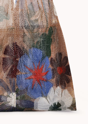 Close-up of the Large Floral Print Mesh Tote by Epice, displaying vibrant color mixes in its floral design against a simple backdrop—a truly luxurious accessory.