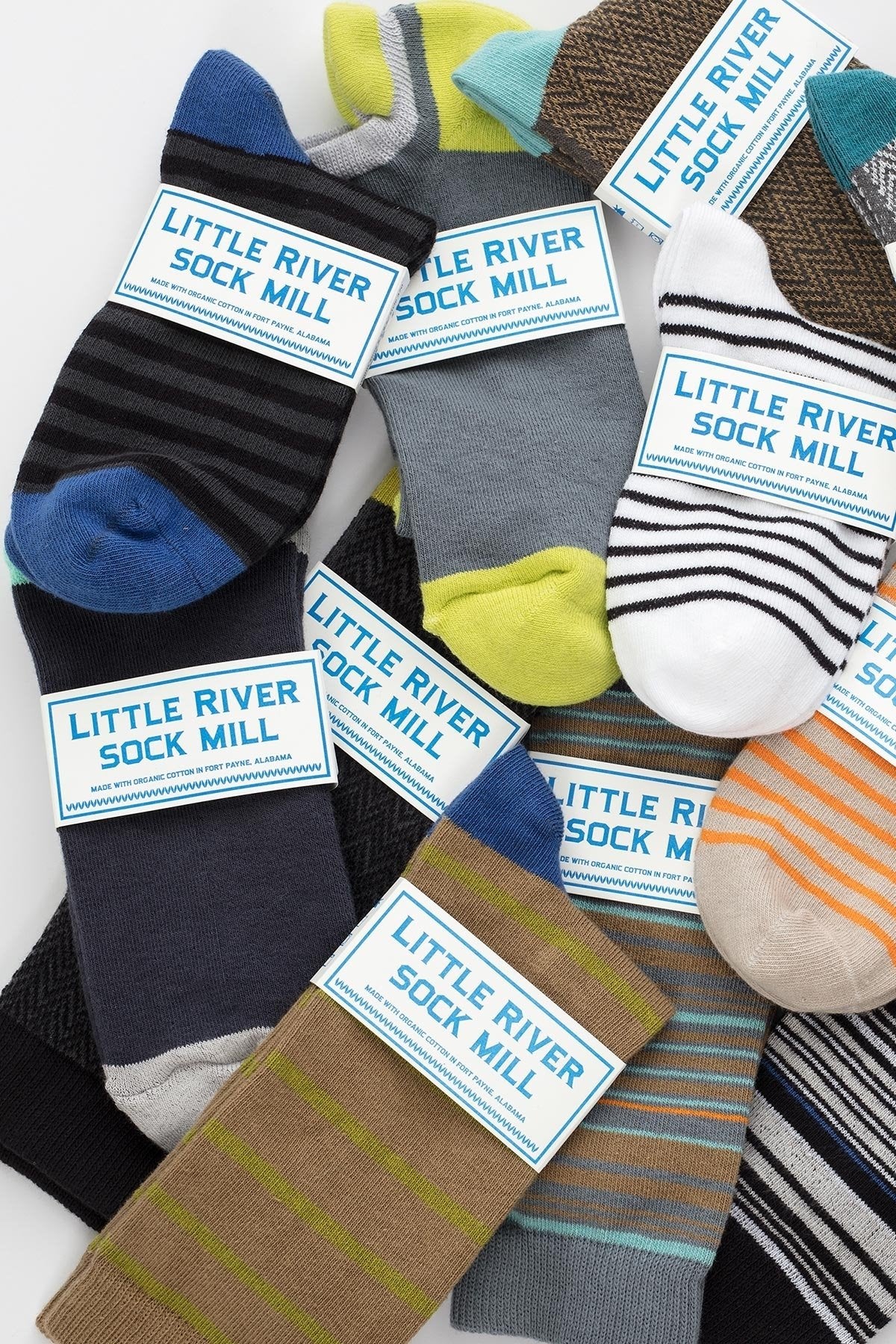 STRIPED BOOTIE SOCK BY LITTLE RIVER SOCK MILL socks by Little River, featuring sustainable materials and assorted colorful stripes, are displayed overlapping on a white background.-668331442257