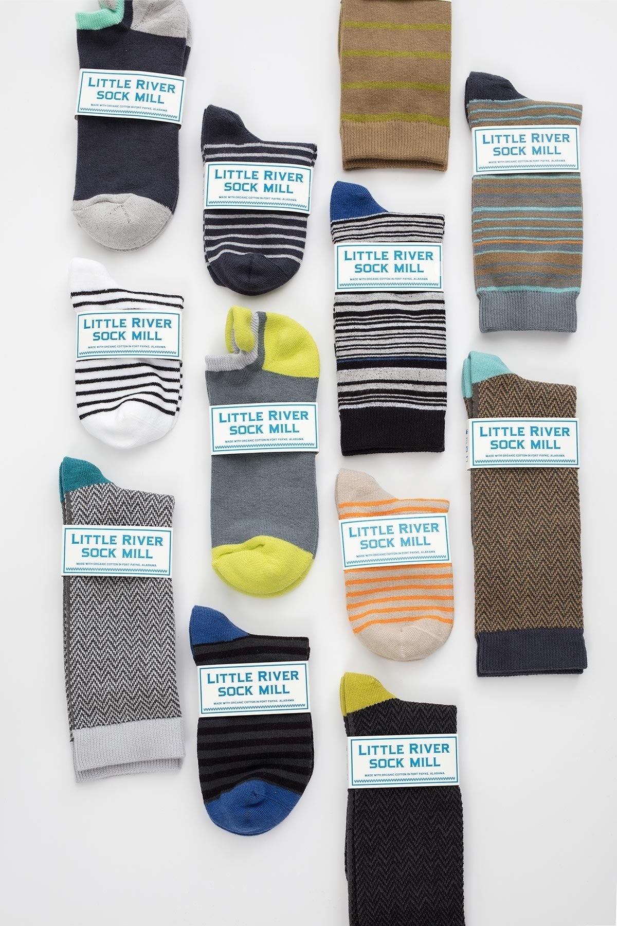 Twelve pairs of MULTI STRIPE CREW SOCK BY LITTLE RIVER SOCK MILL from Little River are neatly arranged on a white background, showcasing a variety of colors and patterns.-668365324369