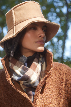 A woman wearing a Velvet by Graham & Spencer REVERSIBLE FAUX SHEARLING BUCKET HAT and scarf.