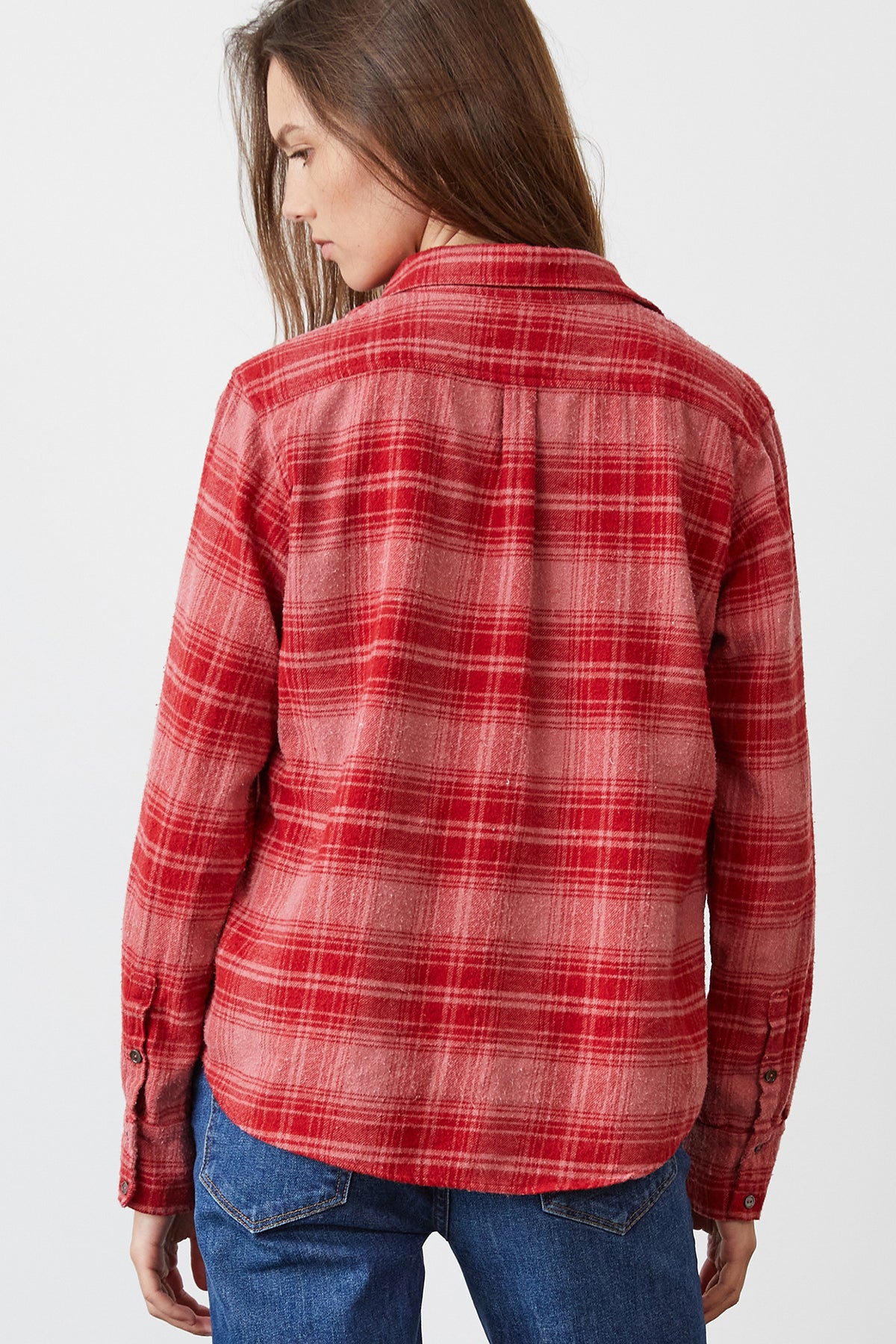 A person with long hair is seen from behind, wearing the RUZ Plaid Button-Up Shirt by Velvet by Graham & Spencer and blue jeans.
