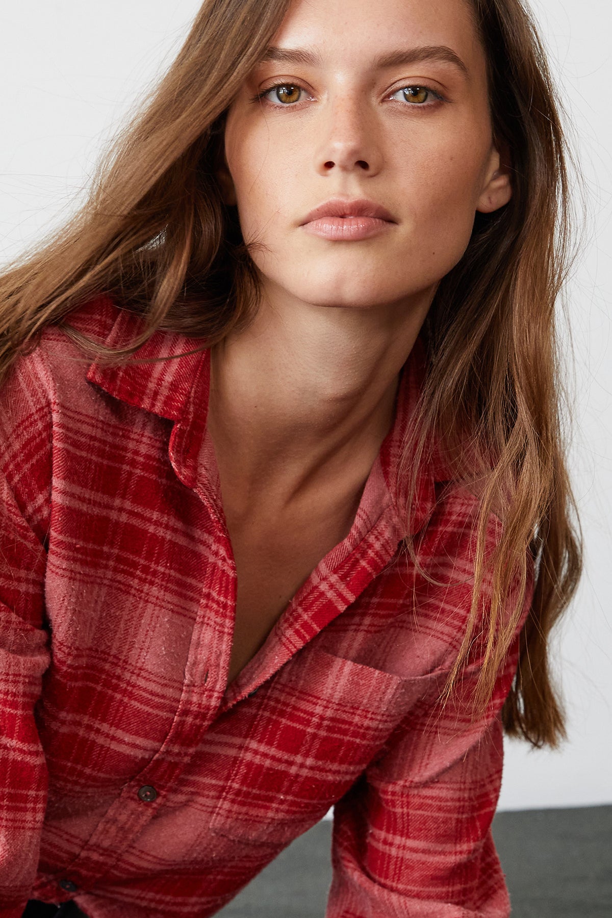 A person with long hair wearing the Velvet by Graham & Spencer RUZ PLAID BUTTON-UP SHIRT in red looks directly at the camera.