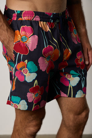 Colt Short front & side in bahama print with bold, multi colored floral pattern with dark background close up detail with model's hand in pocket