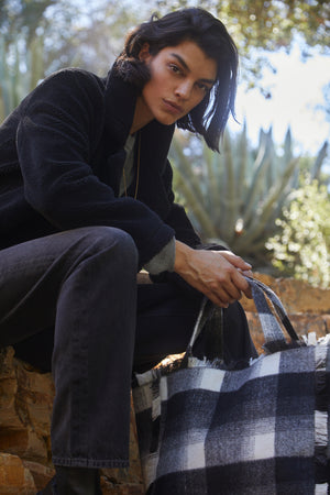 a woman holding a FRAYED FLANNEL WEEKEND BAG by Velvet by Graham & Spencer.