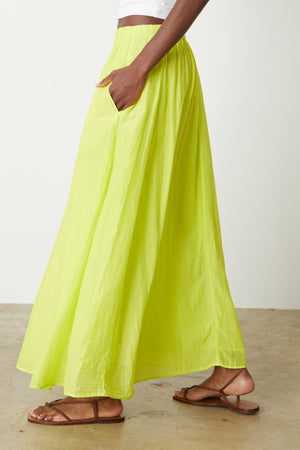 a woman wearing a Velvet by Graham & Spencer Mariela Maxi Skirt and white sandals.