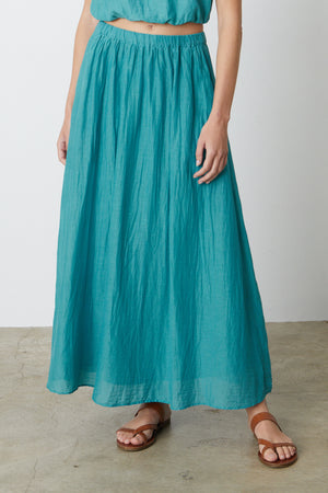 A woman wearing a Velvet by Graham & Spencer MARIELA MAXI SKIRT and sandals.