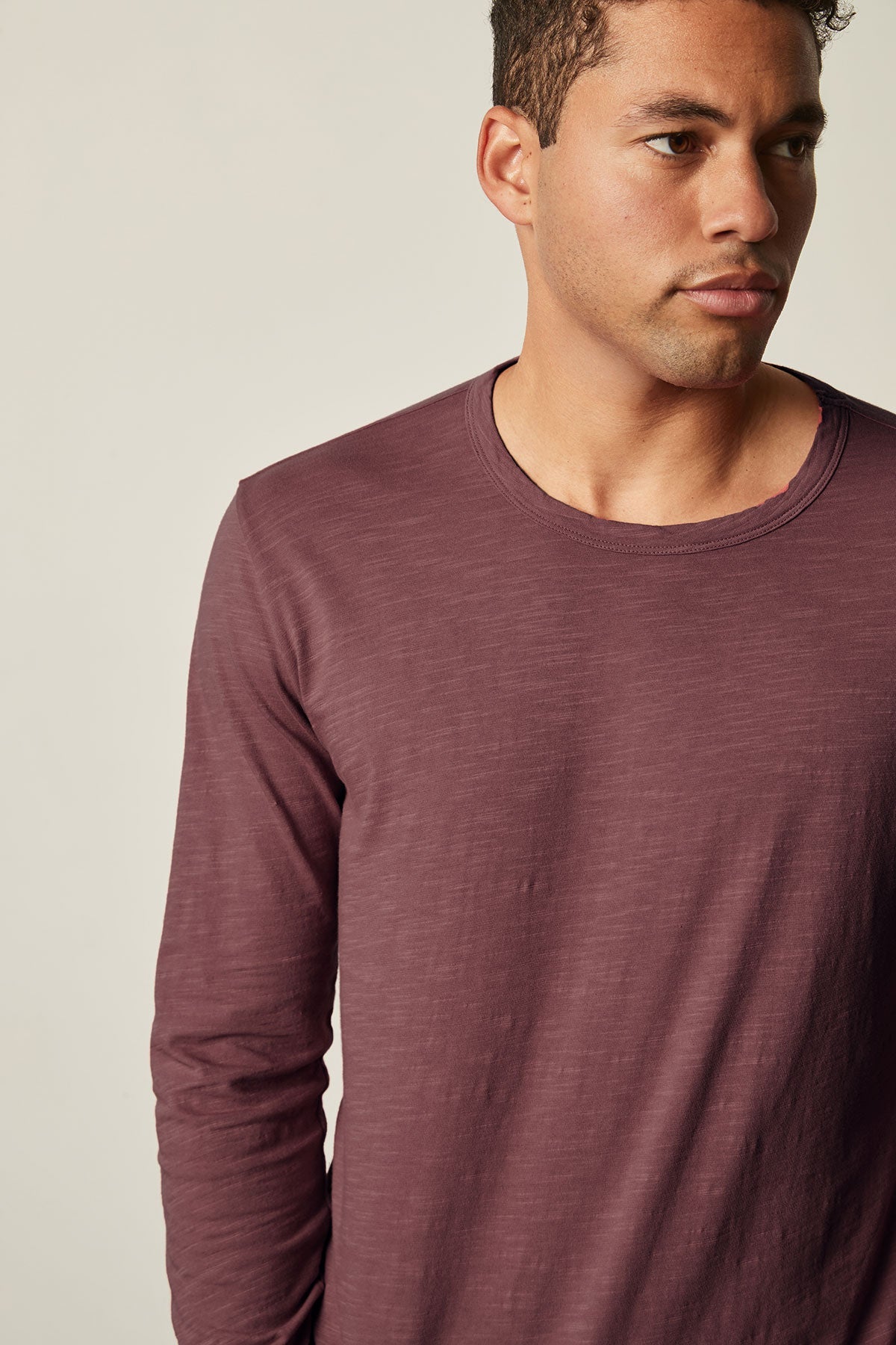 A man wearing a long-sleeve maroon KAI TEE by Velvet by Graham & Spencer with a crew neckline looks to his right against a plain background.-25793842675905