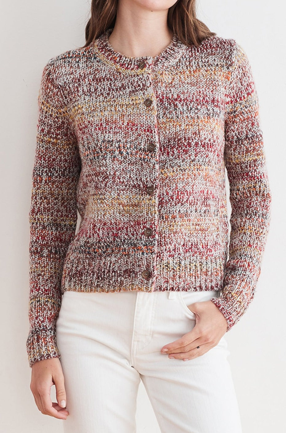 Woman wearing the ALEXIS MARLED CARDIGAN by Velvet by Graham & Spencer, a multi-hued space dye knitted sweater with long sleeves and button closure, paired with white pants.-7238144589905