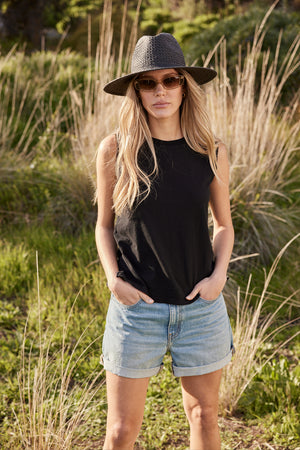 A woman wearing a Velvet by Graham & Spencer VENTED LUXE PACKABLE HAT and denim shorts.