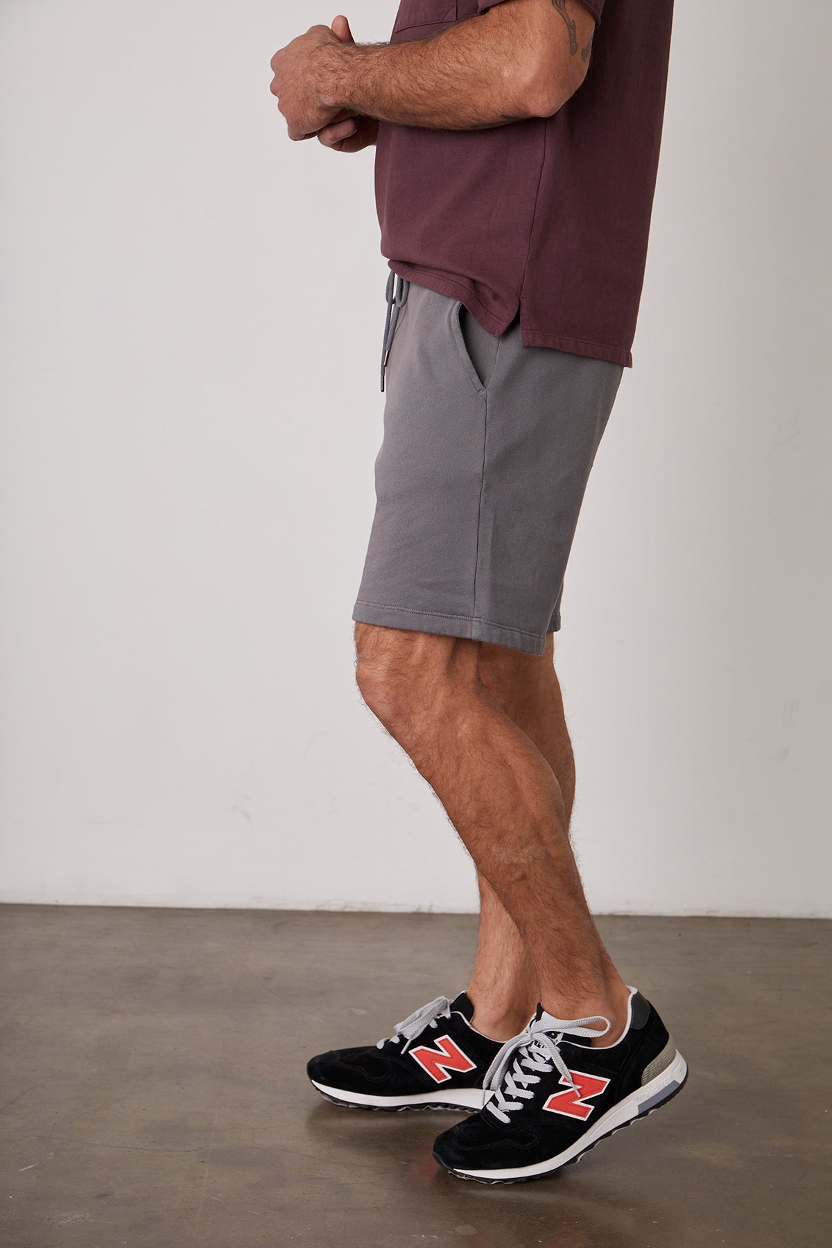 A man wearing Velvet by Graham & Spencer JAXSON DRAWSTRING SHORT and sneakers standing in front of a white wall.-22944804569281