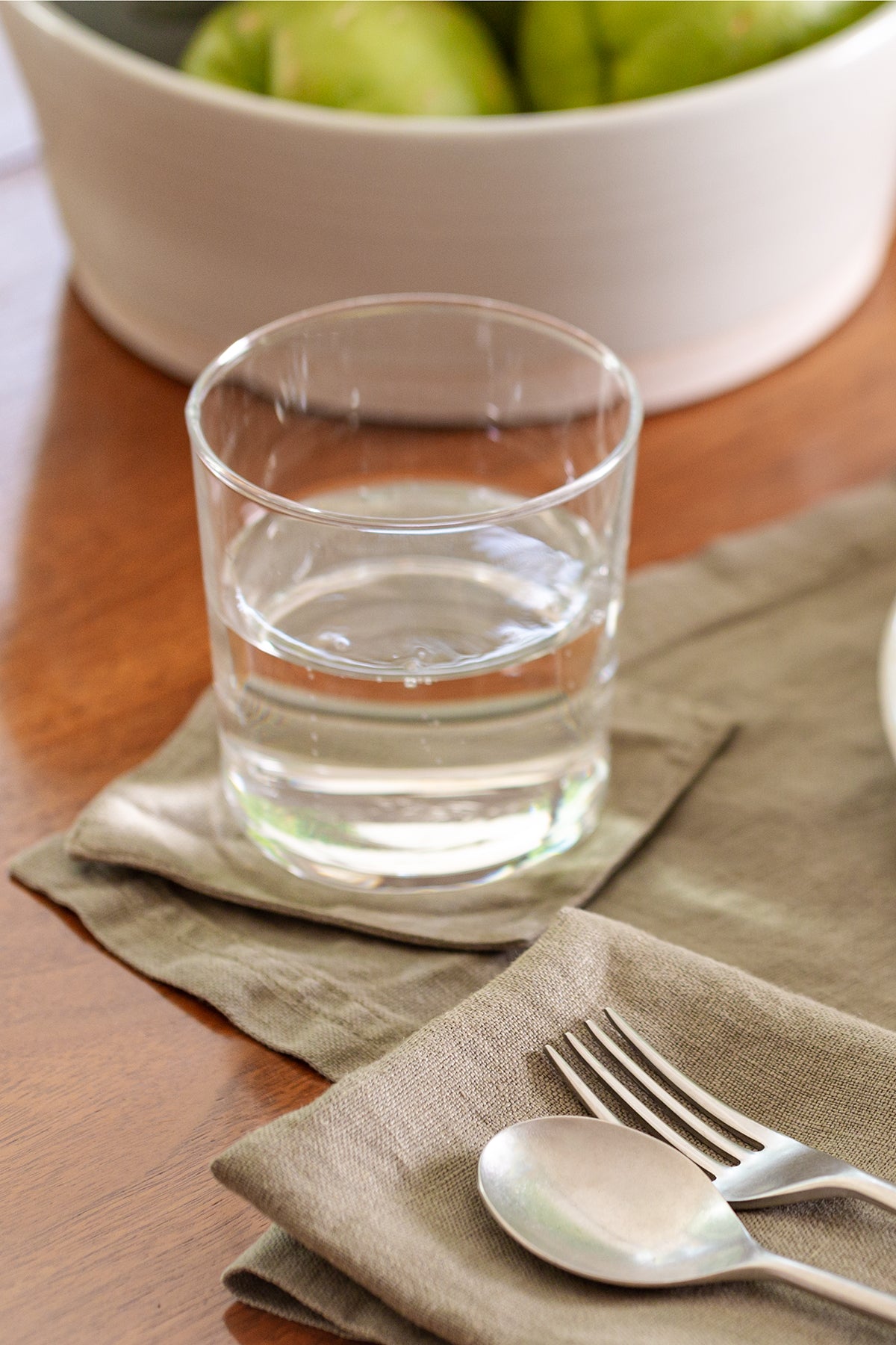 a set of 4 LINEN COASTERS by Jenny Graham Home, with silverware and a glass of water.-15229507993793