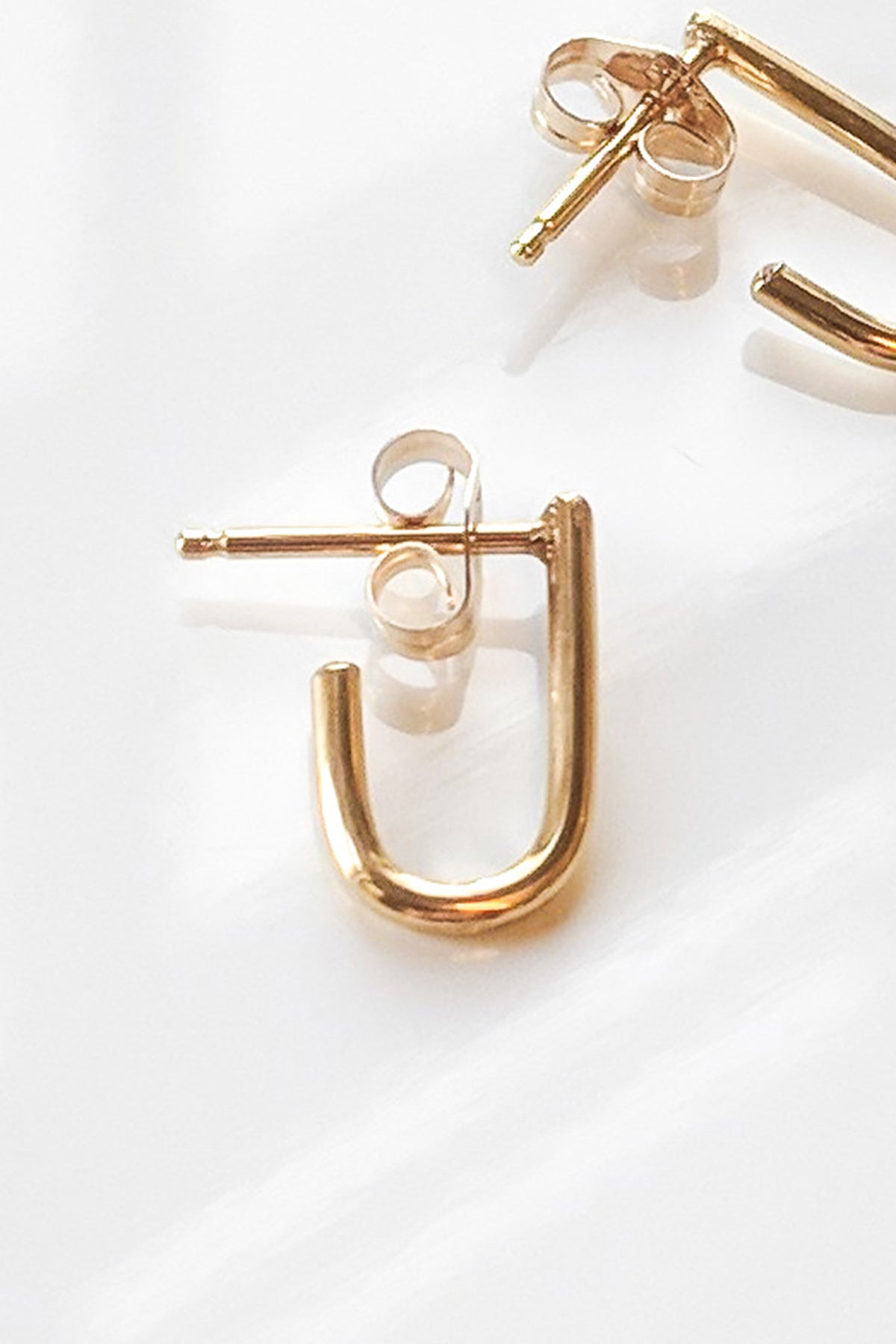Close-up of SELMA GOLD EARRINGS BY THATCH on a white surface, highlighting the modern design and timeless elegance of these gold vermeil earrings by Thatch.