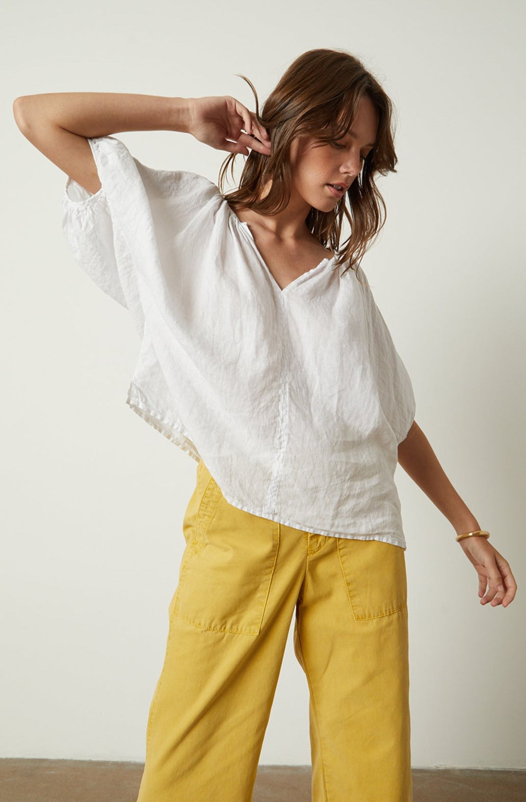The model is wearing a Velvet by Graham & Spencer JANINE LINEN TOP and yellow wide leg pants.