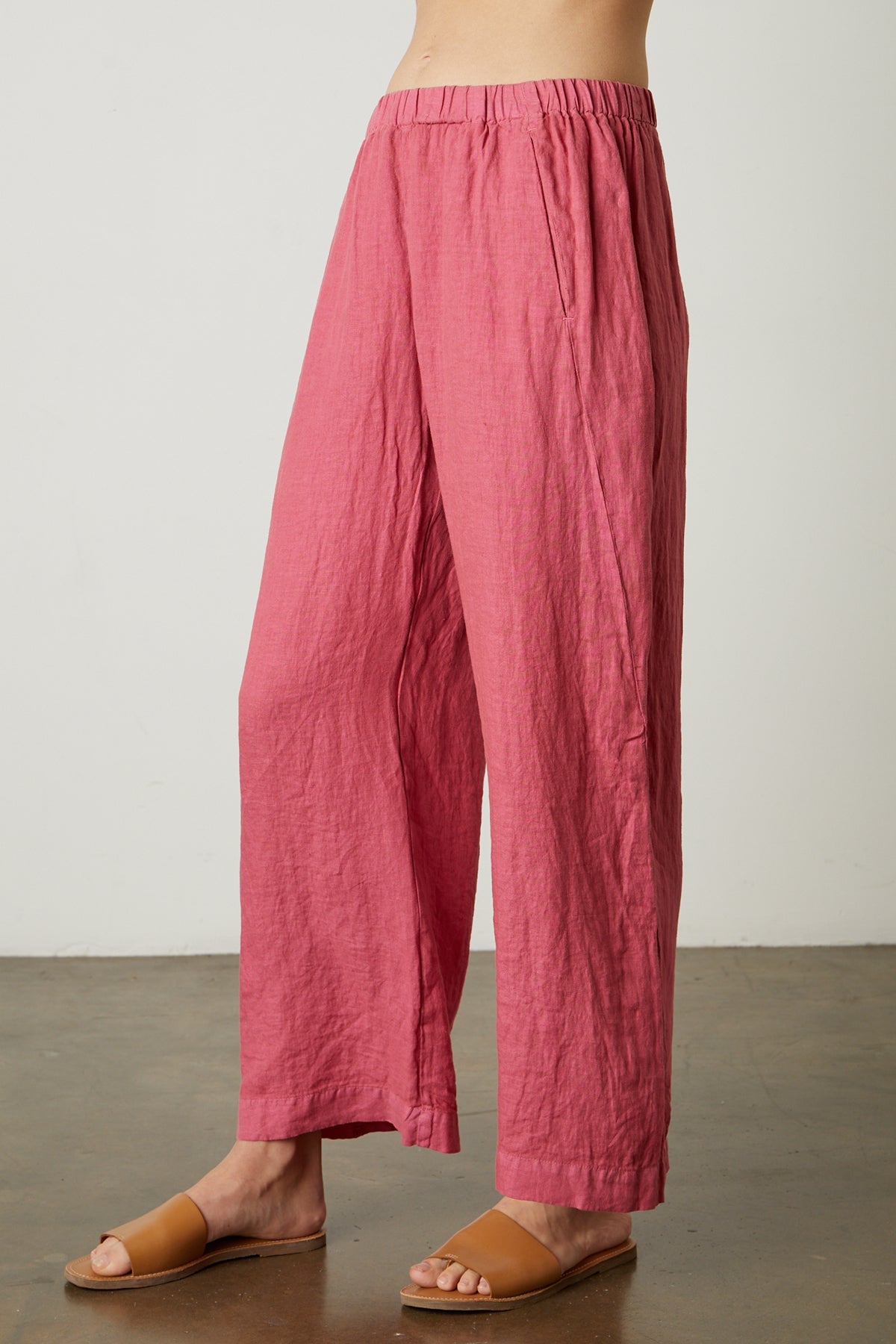 A woman in lightweight pink LOLA LINEN PANT pants and sandals, with elastic waist and pull-on trousers by Velvet by Graham & Spencer.-25329013981377