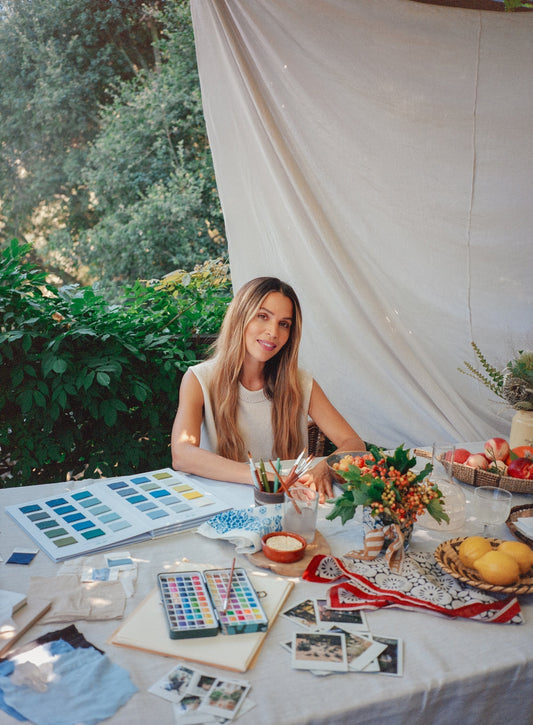 Cleo Wade sits at a table with color swatches and art supplies in a garden setting