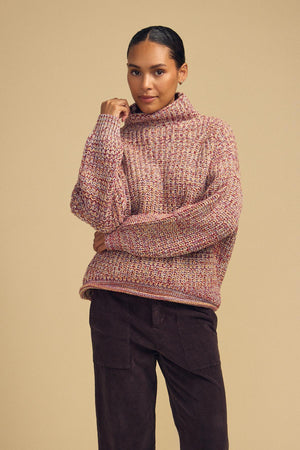 A woman wearing the DENNIE SWEATER by Velvet by Graham & Spencer, paired with dark pants, poses against a plain beige background.