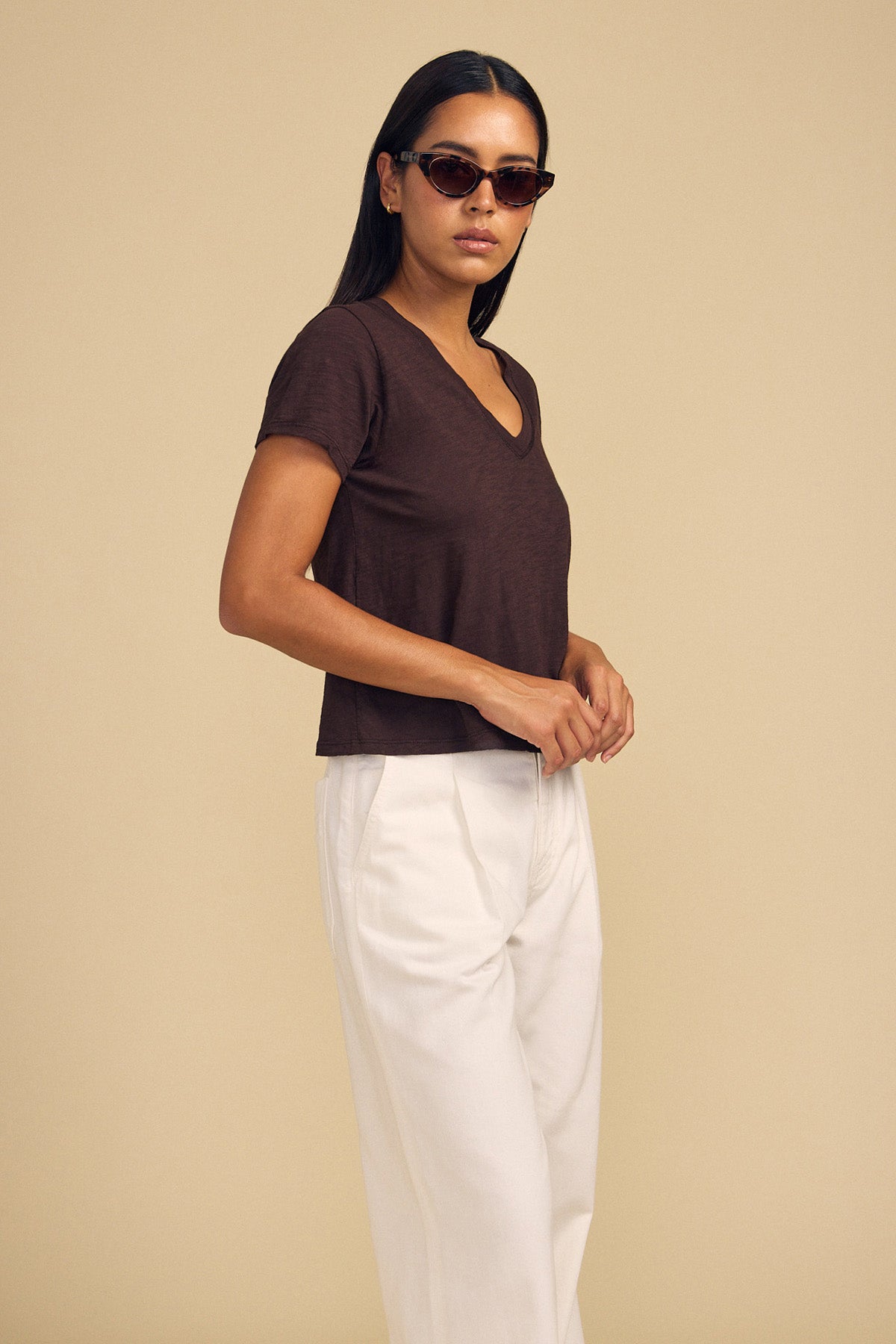 A woman wearing a Velvet by Graham & Spencer ELISHA TEE, white trousers, and dark sunglasses.