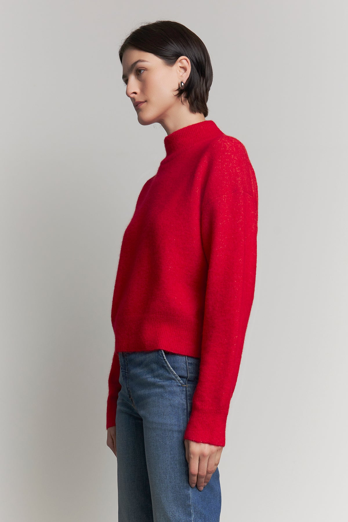 A person wearing the CYPRESS SWEATER by Velvet by Jenny Graham and blue jeans, standing against a light gray background.-38318581481665