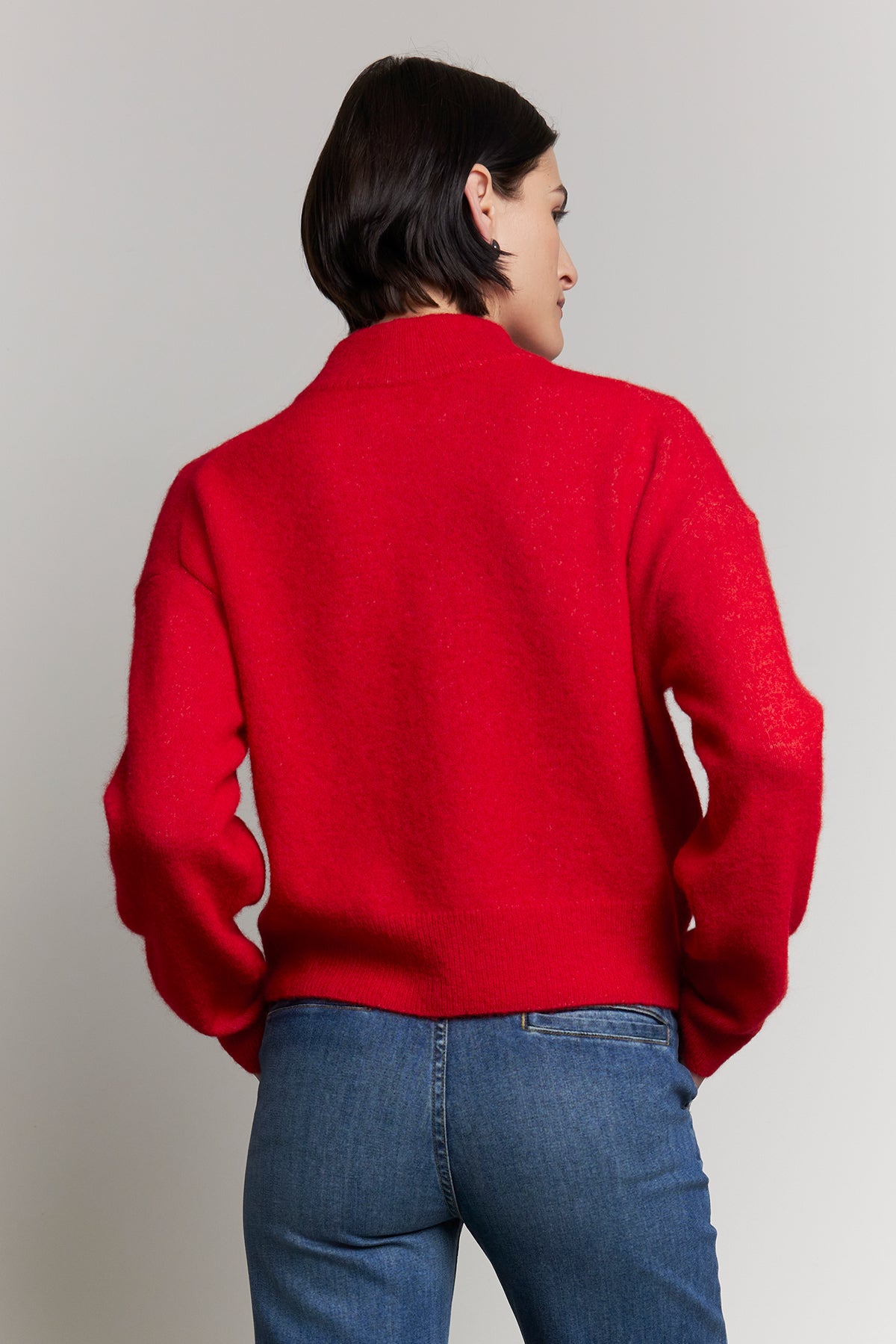 An individual wearing the CYPRESS SWEATER by Velvet by Jenny Graham paired with blue jeans, seen from the back.-38318581416129