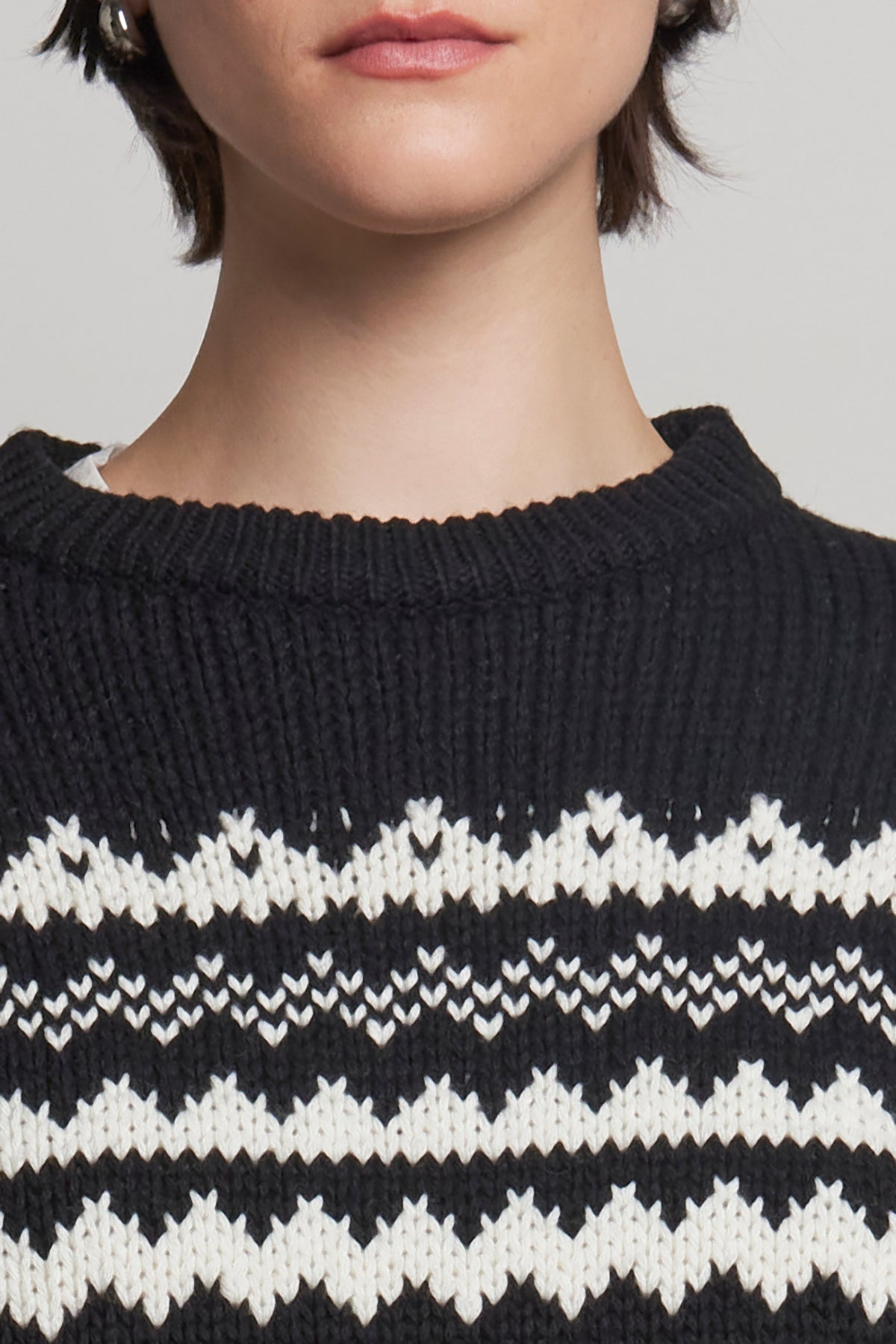 A person wearing the MAYWOOD SWEATER by Velvet by Jenny Graham, featuring a striking black and white Fair Isle pattern in a wool blend knit.-38318585118913