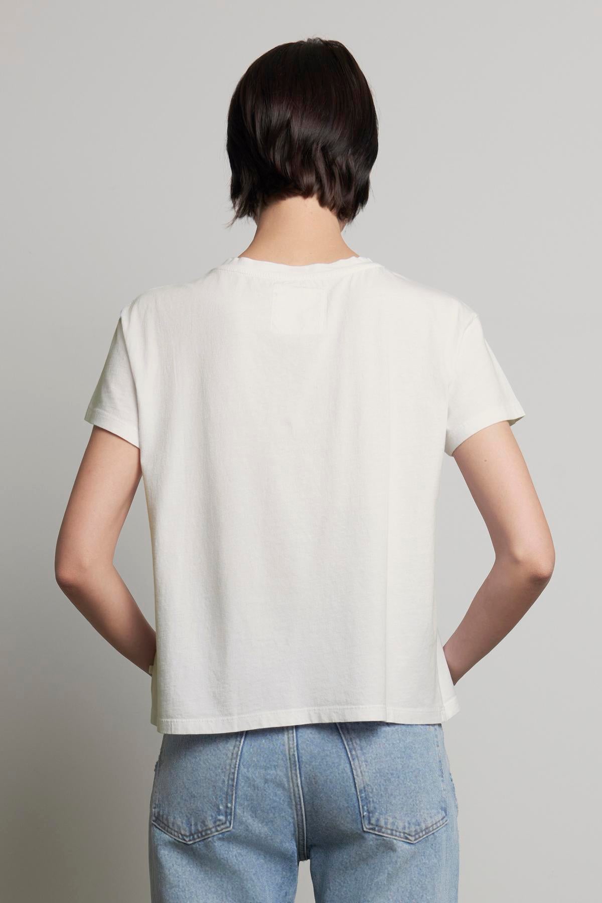 A person with short dark hair is shown from the back, wearing a plain white TOPANGA TEE from Velvet by Jenny Graham and blue jeans.-37817548275905