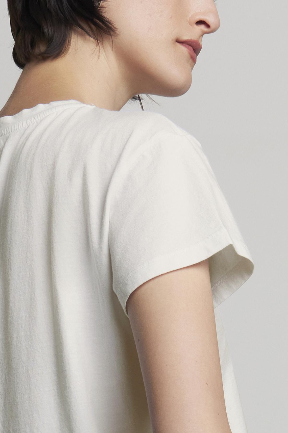 A person with short hair is shown from the side, wearing a relaxed-fit TOPANGA TEE in classic white with short sleeves, made of organic cotton from Velvet by Jenny Graham.-37817548210369